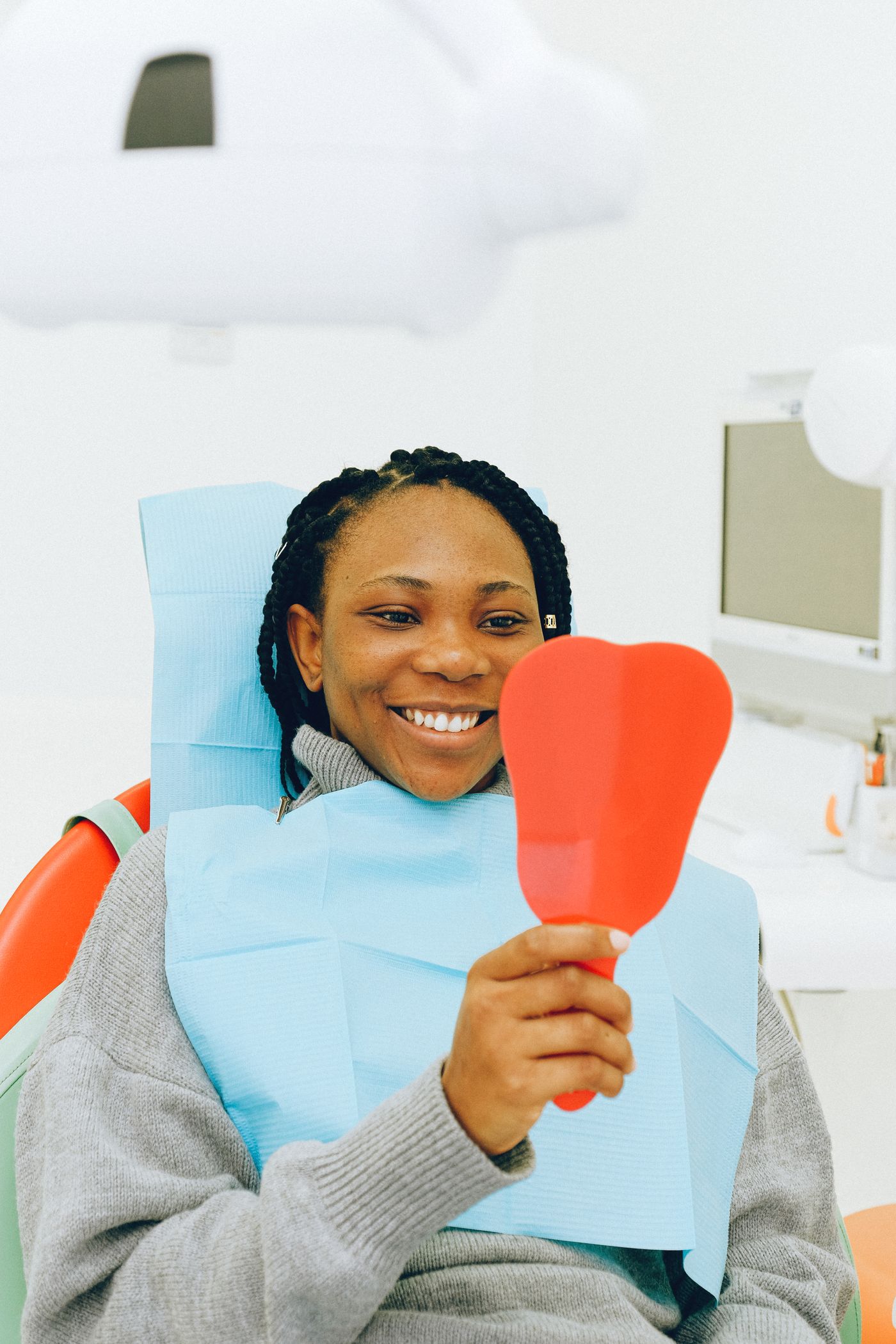 Paciente sonriendo con un espejo en el sillón dental