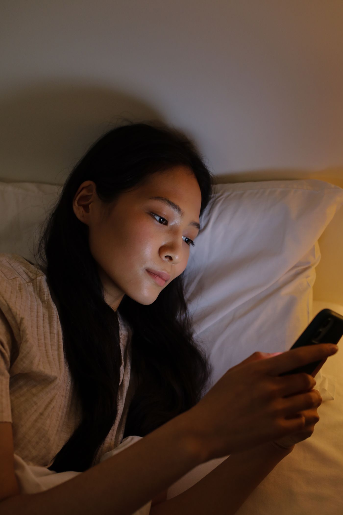 Mujer escribiendo desde el móvil por la noche en la cama